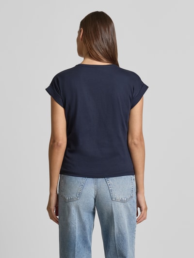 Frauenmodel trägt T-Shirt mit Ziersteinbesatz und Rundhalsausschnitt von Christian Berg Woman aus Reine Baumwolle im Regular-Fit, Rückenlänge 50 cm bei Größe S, Uni-Farbe Dunkelblau, glatte Struktur, Jeans kombiniert, Ganzkörperansicht Rückansicht.
