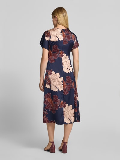 Frauenmodel trägt Midikleid aus Satin von Christian Berg Woman Selection mit floralem Allover-Print in Dunkelblau und Beige, taillierte Passform, Rückenlänge 118 cm, Ganzkörperansicht Rückansicht.