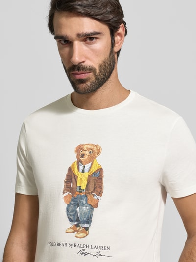 Męski model nosi T-Shirt mit Label-Print von Polo Ralph Lauren z bawełny, regular fit, okrągły dekolt, biały kolor, nadruk misia, zbliżenie na górę ciała.