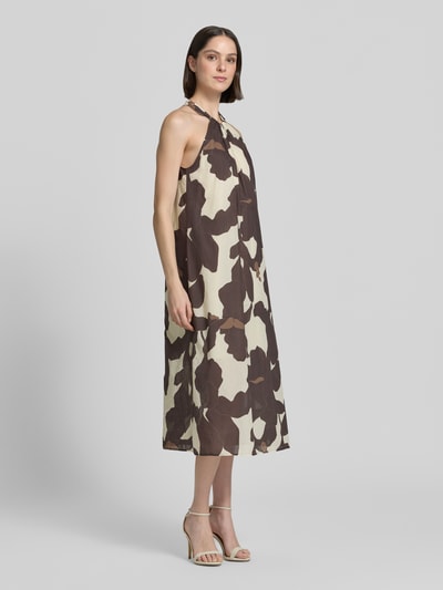 Frauenmodel trägt Neckholder-Midikleid im Allover-Look Modell 'Qowira' von Someday aus reiner Baumwolle mit geradem Schnitt, Muster in Braun und Beige, Ganzkörperansicht von vorne.