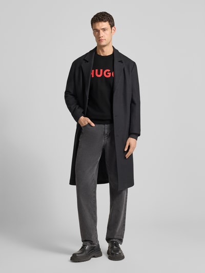 Męski model nosi Sweatshirt mit Label-Detail Modell 'Dem' od HUGO, czarny kolor, bawełna, luźny krój, widok całej sylwetki z przodu.