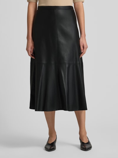 Frauenmodel trägt Midirock in Leder-Optik Modell 'PARIS' von Mango, lockerer Schnitt, Nahtreißverschluss, schwarze Oberfläche, Ganzkörperansicht von vorne.