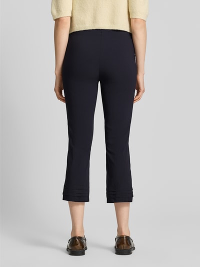 Frauenmodel trägt Caprihose aus Viskose-Mix Modell 'Ina' von STEHMANN in Schwarz, schmaler Schnitt, Drapierungen am Beinabschluss, Rückansicht Ganzkörperansicht. Slim Fit, Bundweite 38 cm, Innenbeinlänge 59 cm, Stretch-Anteil.