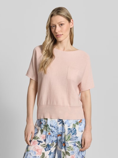 Modelka nosi Strickpullover mit U-Boot-Ausschnitt und Brusttasche od Oui z czystej bawełny, luźny krój, półrękaw, jasnoróżowy, tekstura gładka, dekolt łódkowy, kieszonka na piersi, prążkowany dół, długość tyłu 52 cm, długość rękawa 31 cm, widok przód, zbliżenie górnej części ciała.