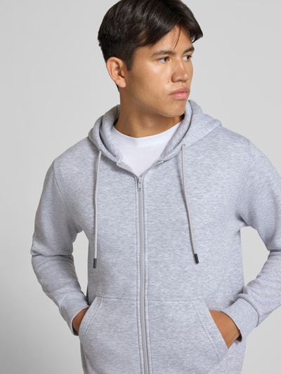 Männermodel trägt Regular Fit Sweatjacke aus Baumwoll-Mix Modell 'BRADLEY' von JACK & JONES in Hellgrau, Nahaufnahme Oberkörper, Kontext: Kapuze mit Tunnelzug, getrennte Känguru-Tasche, elastische Abschlüsse, Rückenlänge 67 cm, Ärmellänge 68 cm