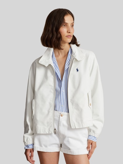Modelka nosi Regular Fit Blouson aus reiner Baumwolle von Polo Ralph Lauren, biały, jednolity, krój regular fit, stójka, długi rękaw, elastyczne mankiety i dół, boczne kieszenie z patką, bawełna, detal z logo, widok całej sylwetki z przodu.
