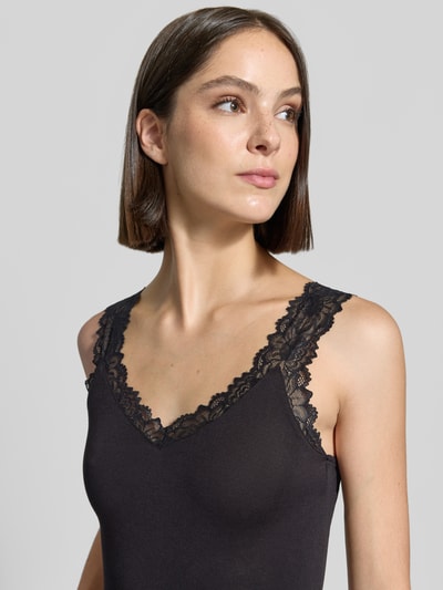Frauenmodel trägt Slim Fit Tanktop aus Viskose-Mix Modell 'ROSA' von VERO MODA in Schwarz mit Spitzenbesatz, Nahaufnahme Oberkörper.