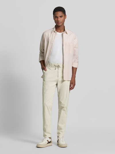 Męski model nosi chinosy Tapered Chino aus Baumwoll-Mix Modell 'CHINO-TAPERED-DS-10' von BOSS Orange, efekt: jednolity kolor, krój tapered fit, szlufki na pasek, zapięcie na guzik i zamek błyskawiczny, tunel (do noszenia wewnątrz lub na zewnątrz), ściągacz: elastyczny, boczne wpuszczane kieszenie, kieszenie z tyłu, mieszanka bawełny, Ganzkörperansicht von vorne.