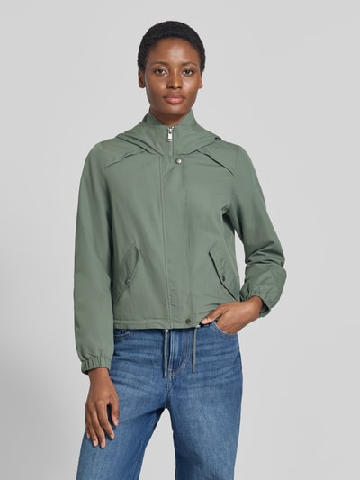 Frauenmodel trägt Regular Fit Parka mit Kapuzenkragen Modell 'ZOA' von VERO MODA in Olivgrün, Jeans, glatte Oberfläche, Ganzkörperansicht von vorne.