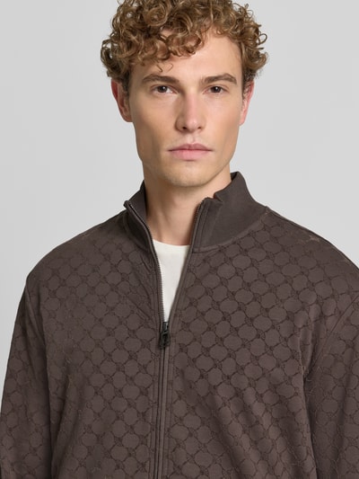 Männermodel trägt Loose Fit Sweatjacke aus Baumwoll-Mix Modell 'Kend' von JOOP! COLLECTION in Braun, Musterstruktur, Nahaufnahme Oberkörper.