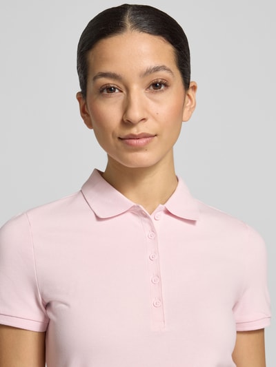 Frauenmodel trägt Slim Fit Poloshirt mit Knopfleiste von Christian Berg Woman aus Baumwoll-Elasthan-Mix, zartrosa Ton, Nahaufnahme Oberkörper.