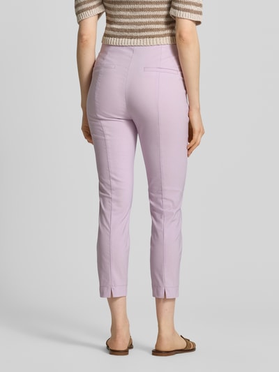 Frauenmodel trägt Slim Fit Stoffhose in verkürzter Passform von Christian Berg Woman, fliederfarben, glatte Textur, Ganzkörperansicht Rückansicht. Elastischer Baumwoll-Mix, Detail Bundweite 39 cm, Innenbeinlänge 66 cm bei Größe 36.
