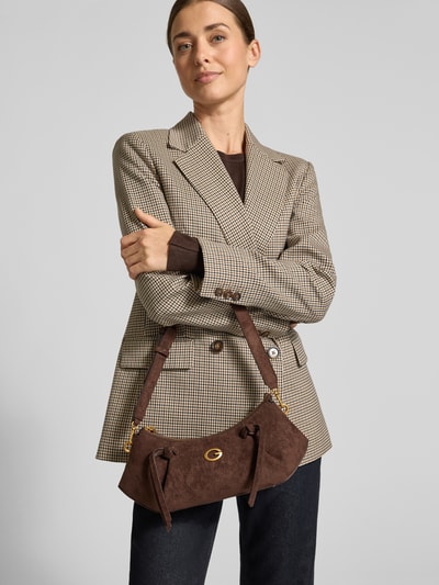 Frauenmodel trägt Handtasche mit Schulterriemen Modell 'ALLEGRA' von GUESS in Braun, strukturierte Oberfläche, Label-Detail, Nahaufnahme Oberkörper. Hauptfach mit Reißverschluss, Maße 28x17x7 cm, Schulterriemen 68 cm.