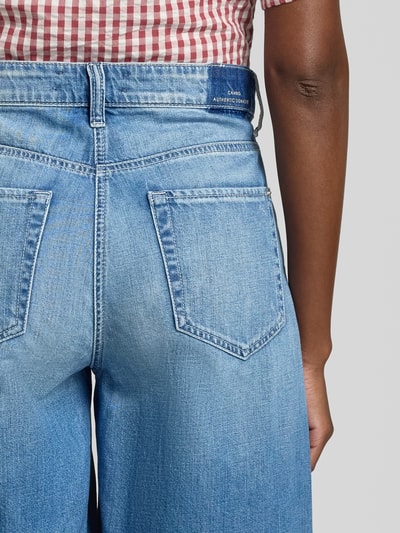 Frauenmodel trägt Loose Fit Jeansshorts aus reiner Baumwolle Modell 'ELIN' von Cambio, Denim-Optik, Nieten, Label-Print, Ganzkörperansicht Rückansicht.