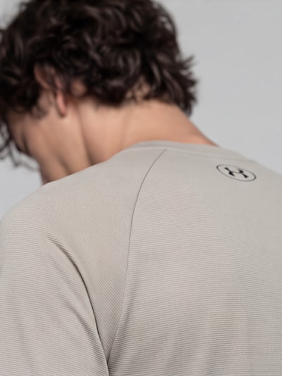 Männermodel trägt Regular Fit Sport-T-Shirt mit Logo-Print von Under Armour in Beige, feine Struktur, Nahaufnahme Rückenansicht. Herren Sport-T-Shirt von Under Armour.
