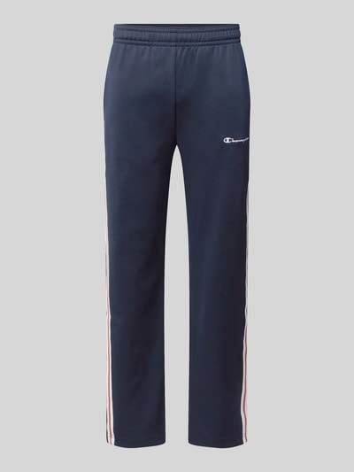 Produktfoto, Sweatpants mit Bordüre von Champion in Dunkelblau mit weiß-roten Seitenstreifen, gerader Schnitt, elastischer Bund, Baumwoll-Material-Mix, Label-Stitching, seitliche Eingrifftaschen, Innenbeinlänge 76 cm bei Größe M.