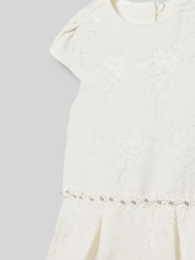 Mädchen trägt Knielanges Kleid mit Rundhalsausschnitt von DANAMADE, cremefarben, Viskose-Mix, Schleifen-Detail, Nahaufnahme Oberkörper.