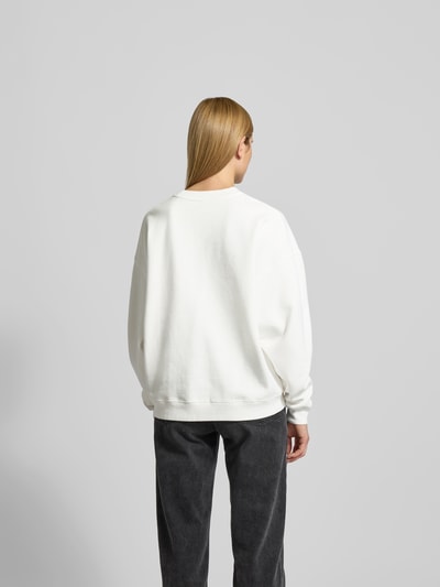 Frauenmodel trägt Oversized Sweatshirt mit Logo-Detail von Anine Bing aus reiner Baumwolle, weiß, Oversized-Fit, elastische Abschlüsse, Rückansicht Ganzkörperansicht. Rückenlänge Größe S: 65 cm.