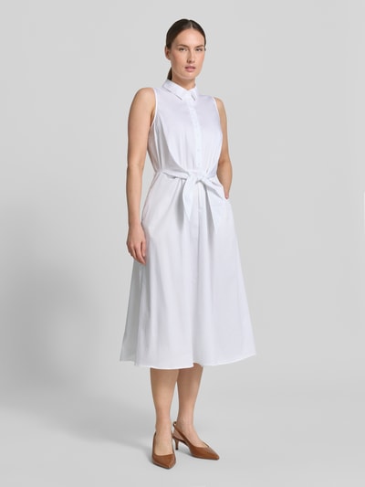 Frauenmodel trägt Hemdblusenkleid aus Satin in Midilänge von Comma, weiß, taillierte Passform, Baumwoll-Mix, Knopfleiste, Taillenband, ärmelloses Design, Ganzkörperansicht von vorne.