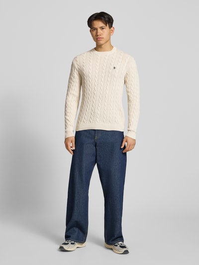 Männermodel trägt Strickpullover mit Zopfmuster und Logo-Stitching von REVIEW, Baumwoll-Mix, Modern Fit, Ganzkörperansicht von vorne.