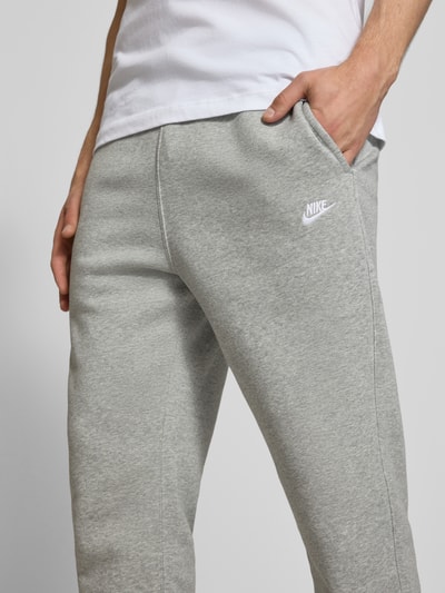 Männermodel trägt Sweatpants mit Label-Stitching und Gesäßtasche von Nike in Hellgrau, Baumwoll-Mix, Nahaufnahme Oberkörper.