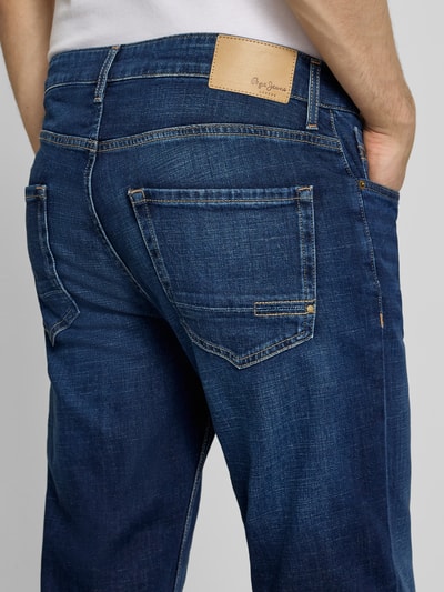 Männermodel trägt Regular Fit Jeans aus Baumwoll-Mix Modell 'CASH' von Pepe Jeans in dunkelblauer Denim-Optik, Label-Patch, Nieten, Kontrastnähte, 5-Pocket-Design, Detailaufnahme Rückansicht.