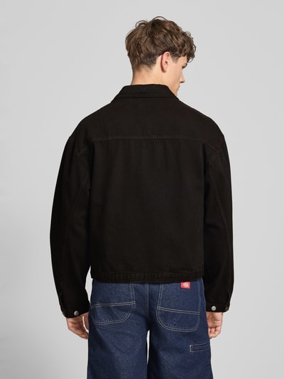 Männermodel trägt schwarze Jeansjacke mit Knopfleiste Modell 'FREELAND' von Edwin aus Reine Baumwolle, Relaxed-Fit, Rückenansicht Ganzkörperansicht. Kontext: Rückenlänge bei Größe M 65 cm, Schulterbreite 56 cm, Brustweite 58 cm, Ärmellänge 62 cm.