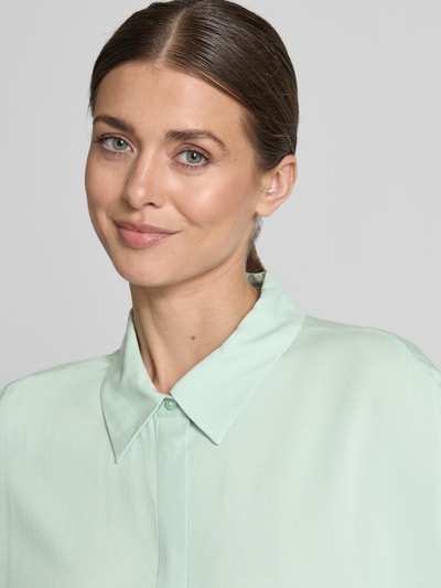 Modelka kobieca ma na sobie Relaxed Fit Kurzarmbluse aus Viskose od Tom Tailor Denim, jednolita z krótkim rękawem, materiał wiskozowy, kolor jasnozielony, widok z przodu, zbliżenie górnej części ciała.