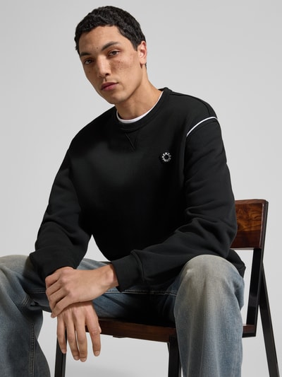 Männermodel trägt Sweatshirt aus reiner Baumwolle von Kenzo in Schwarz mit Label-Detail, lockerer Passform, elastischen Abschlüssen, Rundhalsausschnitt, Rückenlänge bei Größe M: 65 cm, Nahaufnahme Oberkörper.