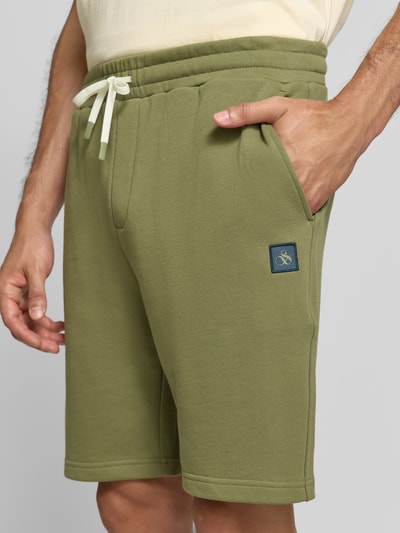 Männermodel trägt Shorts mit Label-Badge und elastischem Bund von Scotch & Soda in Grün, reine Baumwolle, Regular Fit, Nahaufnahme Oberschenkel.