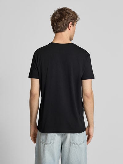 Mężczyzna nosi T-Shirt aus Baumwolle Modell 'BASIC' od Alpha Industries, czarny kolor, krój prosty, bawełna, okrągły dekolt, długość tyłu w rozmiarze M: 67 cm, widok całej sylwetki z tyłu