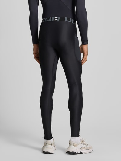 Männermodel trägt Leggings mit Beintasche von Under Armour in Schwarz mit Elastischer-Material-Mix, Elastischer-Logo-Bund, Label-Print, Ganzkörperansicht Rückansicht