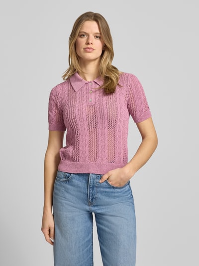 Frauenmodel trägt Slim Fit Poloshirt in Strick-Optik Modell 'Ajour' von Review in Rosa mit Loch-Optik und Polo-Kragen, Ganzkörperansicht von vorne.