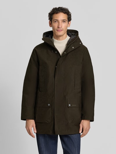 Männermodel trägt Regular Fit Funktionsjacke mit Kapuze von Barbour in Dunkelbraun, große Taschen, glatte Textur, Ganzkörperansicht von vorne. Herren Funktionsjacke von Barbour.