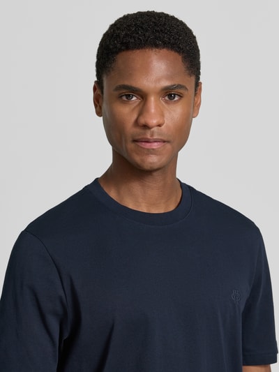 Mężczyznamodel nosi Regular Fit T-Shirt mit Logo-Stitching von MCNEAL z bawełny, okrągły dekolt, krój regular fit, długość tyłu 70 cm, rozmiar M, zbliżenie na górną część ciała