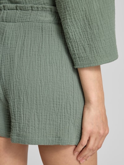 Frauenmodel trägt Loose Fit Shorts aus reiner Baumwolle Modell 'NATALI' von Vero Moda, grün, Crêpe-Textur, unifarben, Nahaufnahme Hüfte