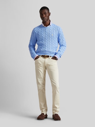 Männermodel trägt Regular Fit Strickpullover aus reiner Baumwolle von Polo Ralph Lauren in Hellblau mit Zopfmuster, unifarben, Ganzkörperansicht von vorne