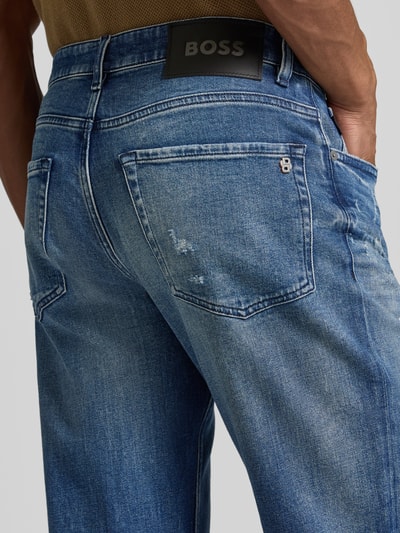 Männermodel trägt Regular Fit Straight Leg Jeans aus Baumwoll-Mix Modell 'RE.MAINE BO VISIBLE' von BOSS Orange, Used-Look, Material Denim, Label-Stitching, Logo-Detail, 5-Pocket-Design, Farbe Blau, Nahaufnahme Rückansicht.