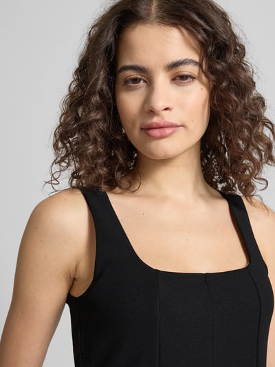 Modelka nosi Slim Fit Top in Falten-Optik von Gina Tricot, elastyczna mieszanka materiałów, krój slim fit, efekt fałd, krój bez rękawów, długość tyłu w rozmiarze S: 50 cm, zbliżenie na górną część ciała z przodu.