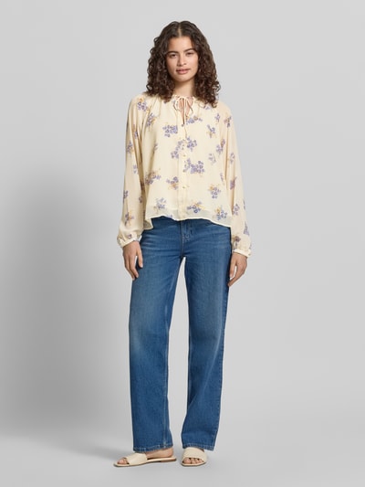 Frauenmodel trägt Relaxed Fit Chiffon-Bluse mit Allover-Muster Modell 'FUSINA' von Only in Creme mit fliederfarbenen Blumen, Ganzkörperansicht von vorne, Kontext: Damen Chiffon-Bluse, Optik:Allover-Muster, Passform:Relaxed-Fit, Rundhals, Raffung, Bindeband, Langarm, Ballonärmel, Knopf mit Öse, Materialverarbeitung:Chiffon.