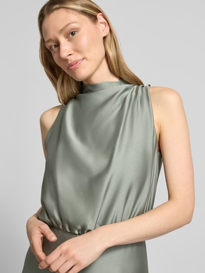 Frauenmodel trägt Cocktailkleid mit Stehkragen von Swing in zartem Grün, glatte Textur, taillierte Passform, Nahaufnahme Oberkörper.