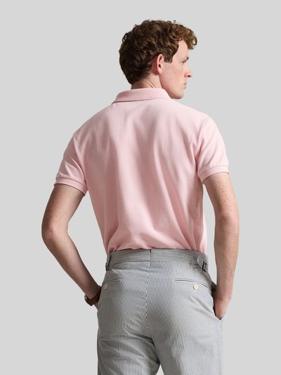 Männermodel trägt Regular Fit Poloshirt aus reiner Baumwolle von Polo Ralph Lauren, lichtroze, effen piqué, korte mouw, logo detail, polokraag, V-hals, knoopsluiting, geribbelde zooms, asymmetrische splitten, rugaanzicht.