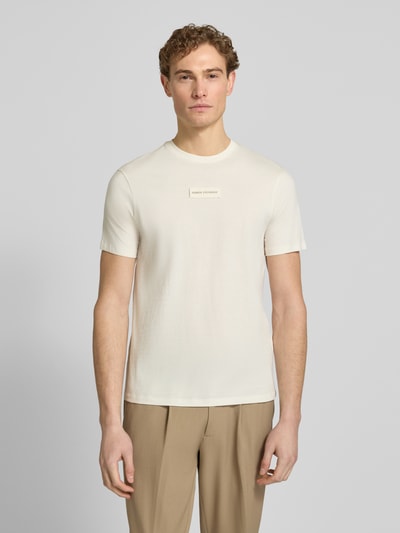Männermodel trägt T-Shirt mit Label-Detail und Rundhalsausschnitt von ARMANI EXCHANGE in Beige, Regular Fit, reine Baumwolle, Ganzkörperansicht von vorne.