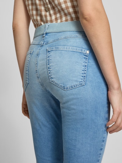 Kobiece model nosi spodnie capri Caprihose mit elastischem Bund Modell 'AnnaCapri Sporty' von Angels, mieszanka bawełny z dodatkiem streczu, krój slim fit, jasnoniebieski denim, faktura gładka, szerokość w rozmiarze 36: 39 cm, długość wewnętrzna nogawki w rozmiarze 36: 46 cm, detal kieszeni, zdjęcie z tyłu, zbliżenie na biodra i pas.