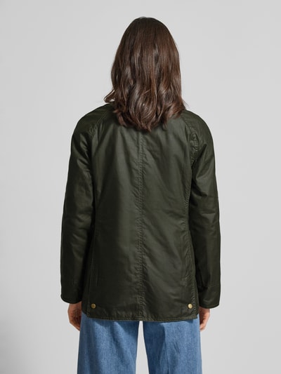 Frauenmodel trägt Wachsjacke aus reiner Baumwolle von Barbour, Regular-Fit Optik, glatte feine Webstruktur, Ganzkörperansicht Rückansicht.