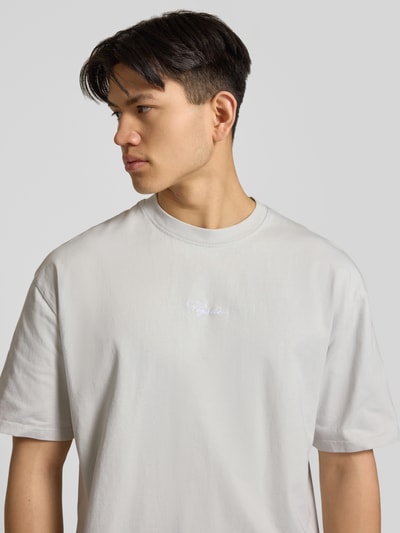 Männermodel trägt Oversized T-Shirt mit 1/2-Arm Modell 'Towson' von Pegador aus reiner Baumwolle, hellgrau, Nahaufnahme Oberkörper.
