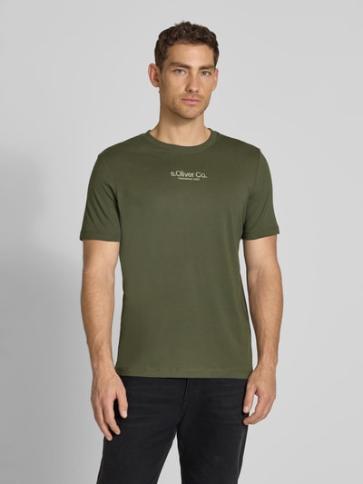 Mężczyzna nosi Regular Fit T-Shirt aus reiner Baumwolle von s.Oliver RED LABEL, kolor jednolity, krój regular fit, nadruk z logo, dekolt okrągły, krótki rękaw, materiał bawełniany, widok całej sylwetki z przodu.
