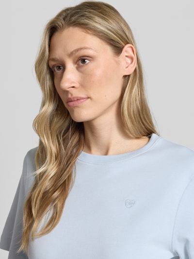 Frauenmodel trägt Damen T-Shirt mit Logo-Stitching Modell 'SVEHA' von Oui aus reiner Baumwolle in Hellblau, Nahaufnahme Oberkörper.