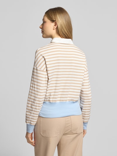 Frauenmodel trägt Regular Fit Poloshirt mit breitem Bund von Marc Cain in Beige-Weiß gestreift, hellblauer Bund, Ganzkörperansicht Rückansicht.
