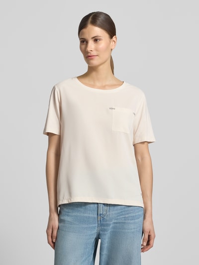 Kobiece model prezentuje T-Shirt aus Viskose-Mix mit Brusttasche od monari w kolorze jasnokremowym, luźny krój, kieszonka z przodu, aplikacja z dżetami, okrągły dekolt, długość pleców w rozmiarze 36: 56 cm, widok całej sylwetki z przodu.